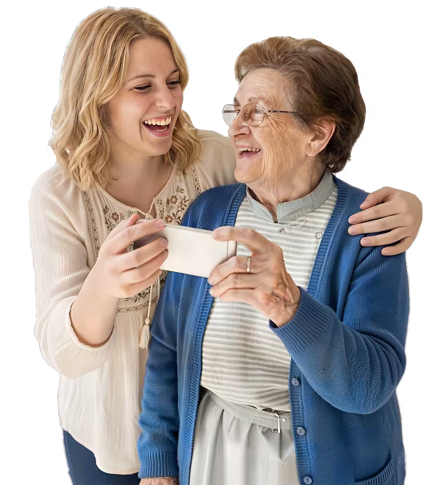 Junge Alltagshelferin und ältere Dame lachen gemeinsam beim Anschauen eines Fotos